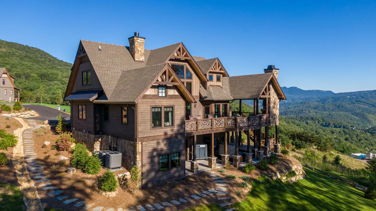 This exterior image captures the house nestled against a backdrop of lush mountains and manicured landscaping. The open setting hints at the surrounding natural environment and the spaciousness of the community. The image evokes a sense of arrival and anticipation for outdoor adventure, showcasing the house as a gateway to the mountains beyond.